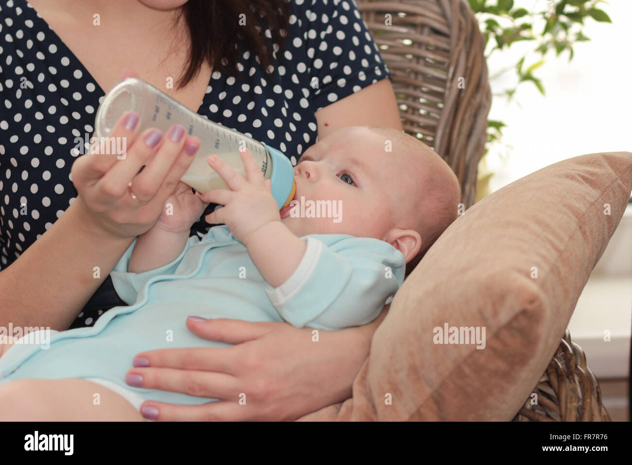 Madre en la casa materna de bebé con una botella de leche Foto de stock