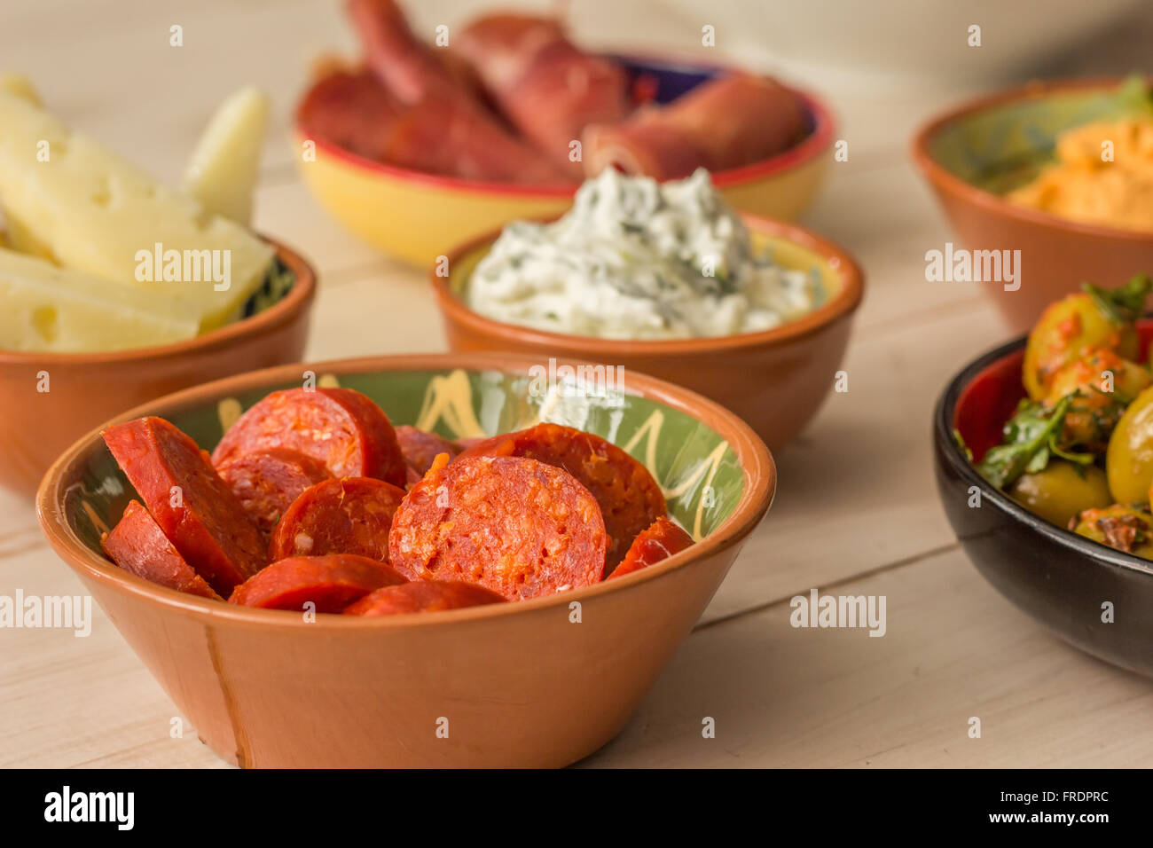 Tapas, tzatziki, manchego, chorizo, aceitunas y el jamón en una tabla blanca Foto de stock