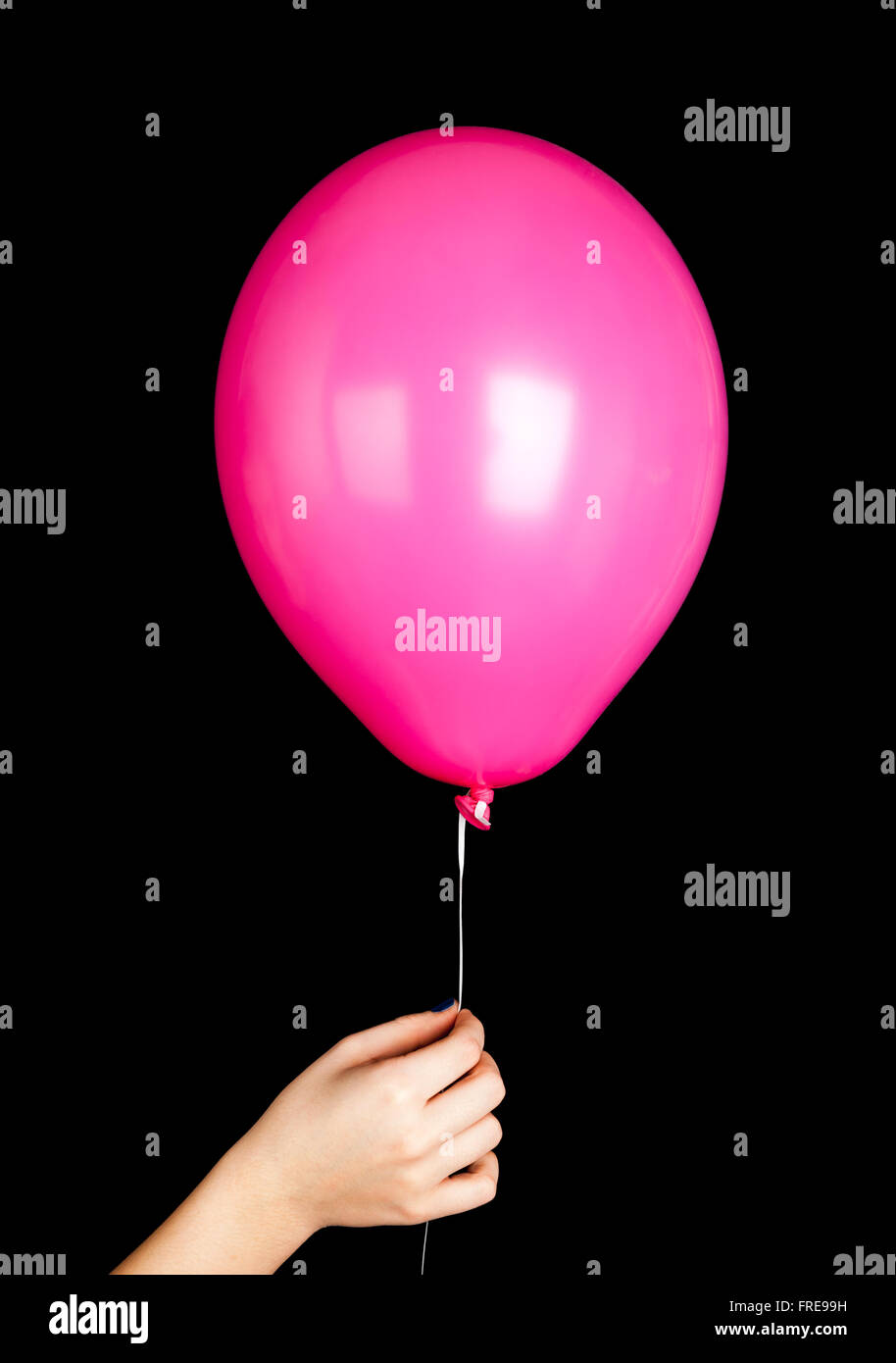 Niño mano sosteniendo globo rosa aislado sobre fondo negro Foto de stock