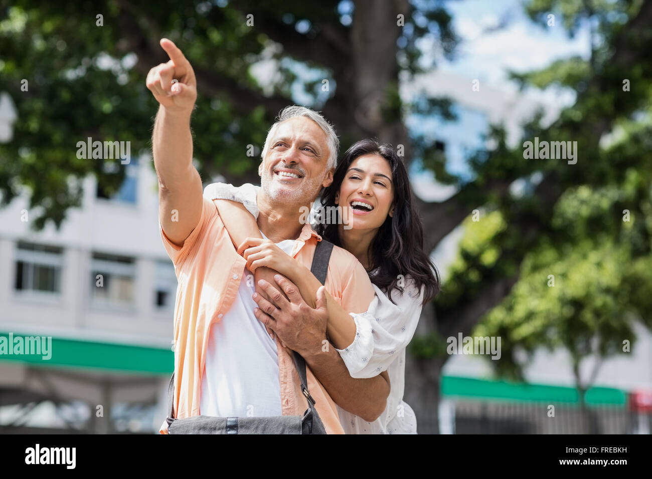 El hombre apuntando mientras la mujer abrazando a él desde atrás Foto de stock