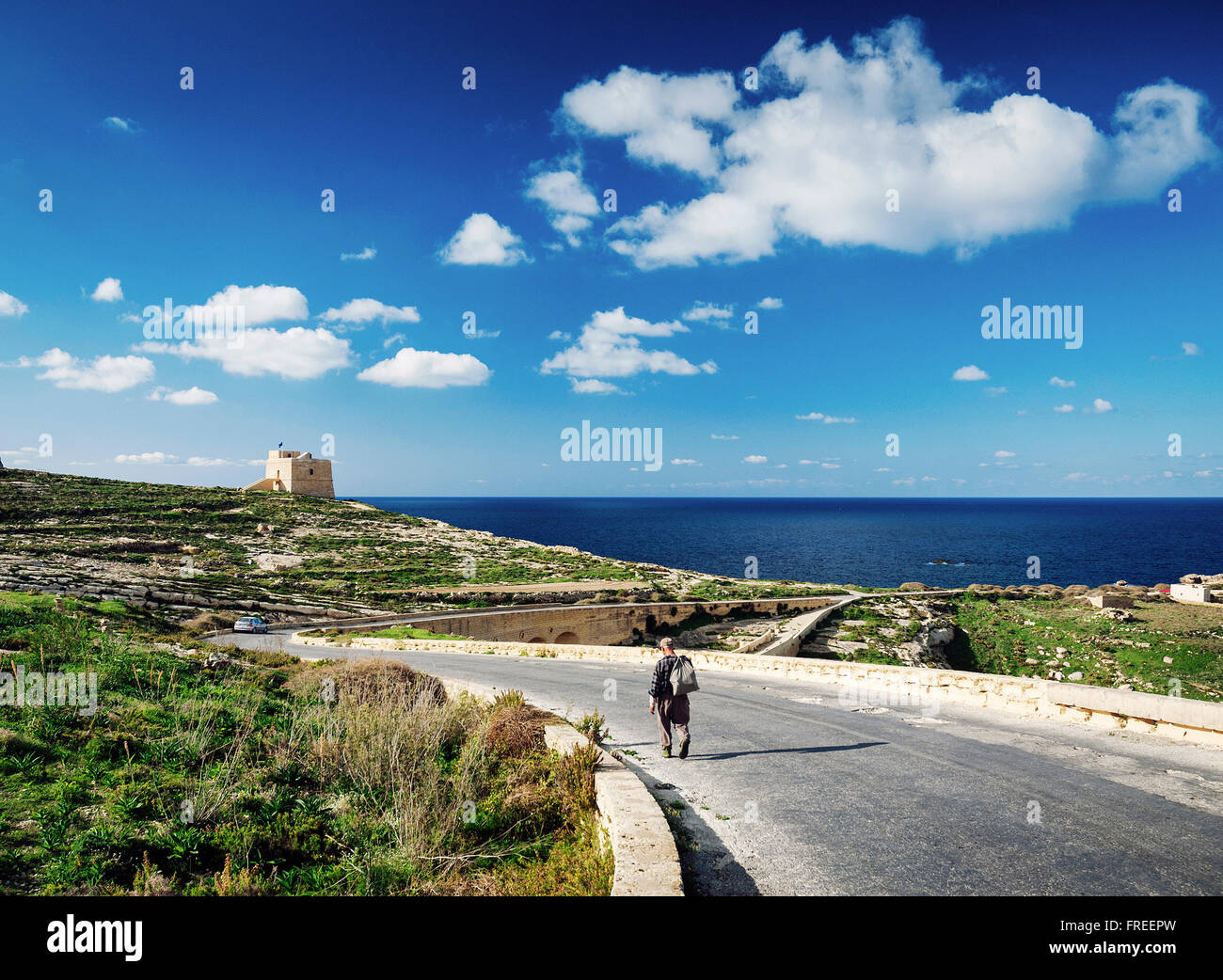 Pastor en la carretera cerca de Fort y la costa mediterránea vista de la isla de Gozo en Malta Foto de stock