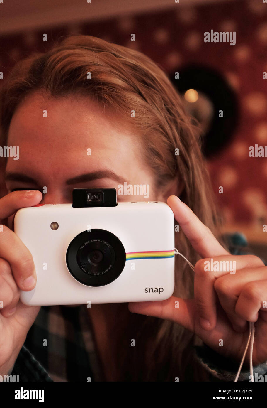 Mujer joven con una cámara de fotos Polaroid para tomar fotografías de  impresión instantánea Fotografía de stock - Alamy
