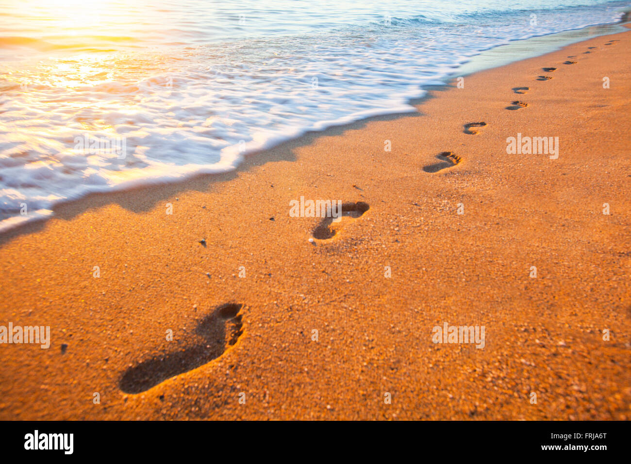 Playa, olas y huellas en el ocaso del tiempo Foto de stock