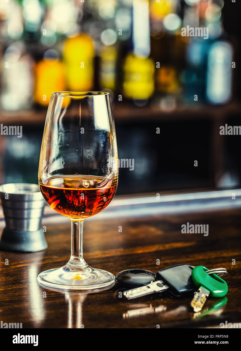 El alcoholismo. Taza de coñac o brandy mano las llaves del coche y conductor irresponsable. Foto de stock