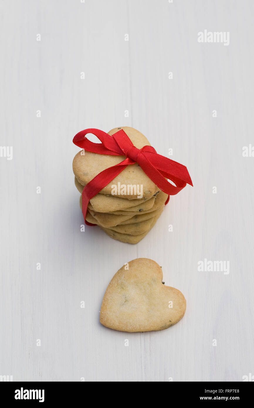 Una pila de galletas en forma de corazón atado con una cinta roja. Foto de stock