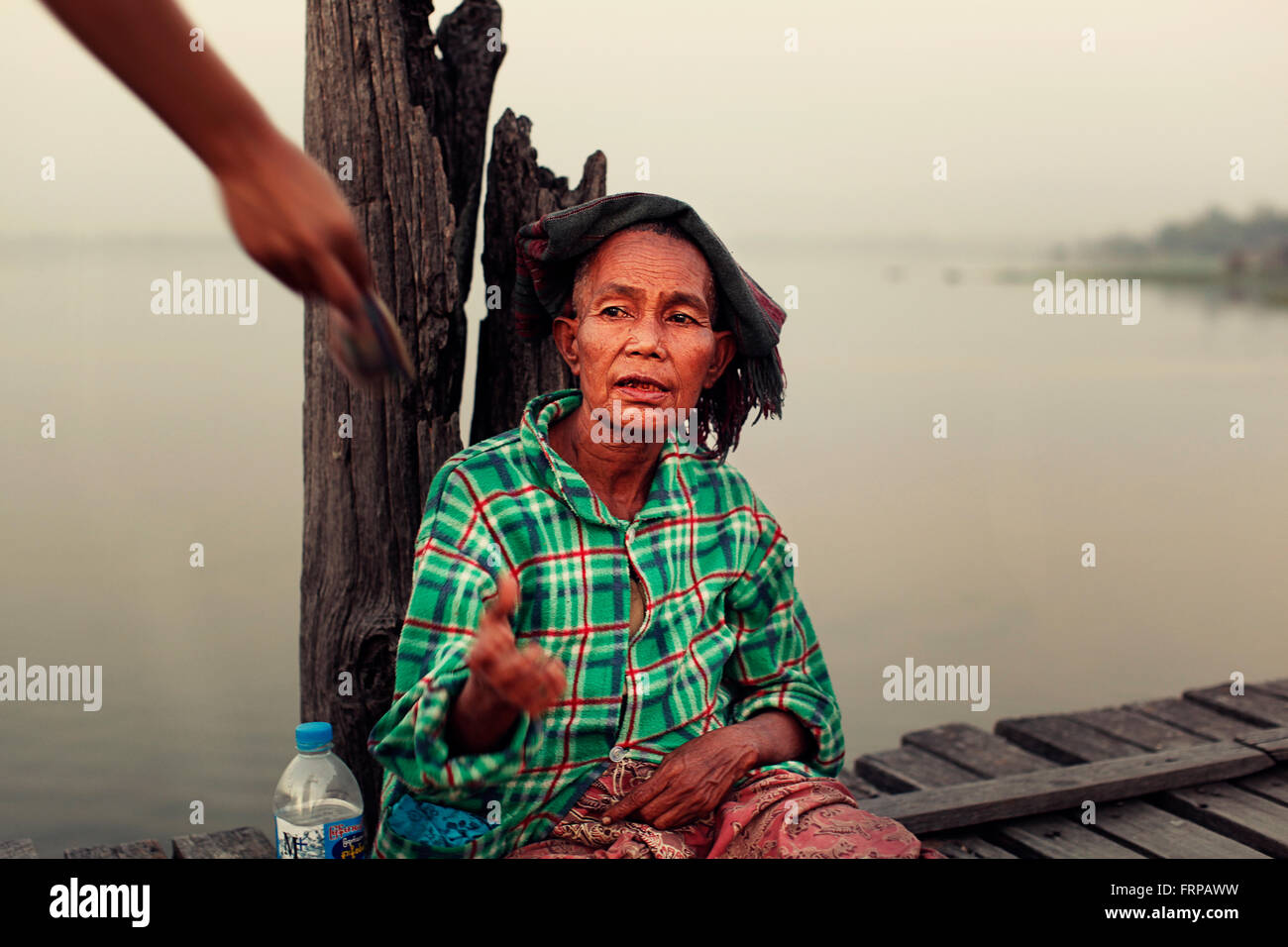 Una mujer en U-Bein Puente, obteniendo ayuda de los visitantes. Myanmar Amarapura Foto de stock