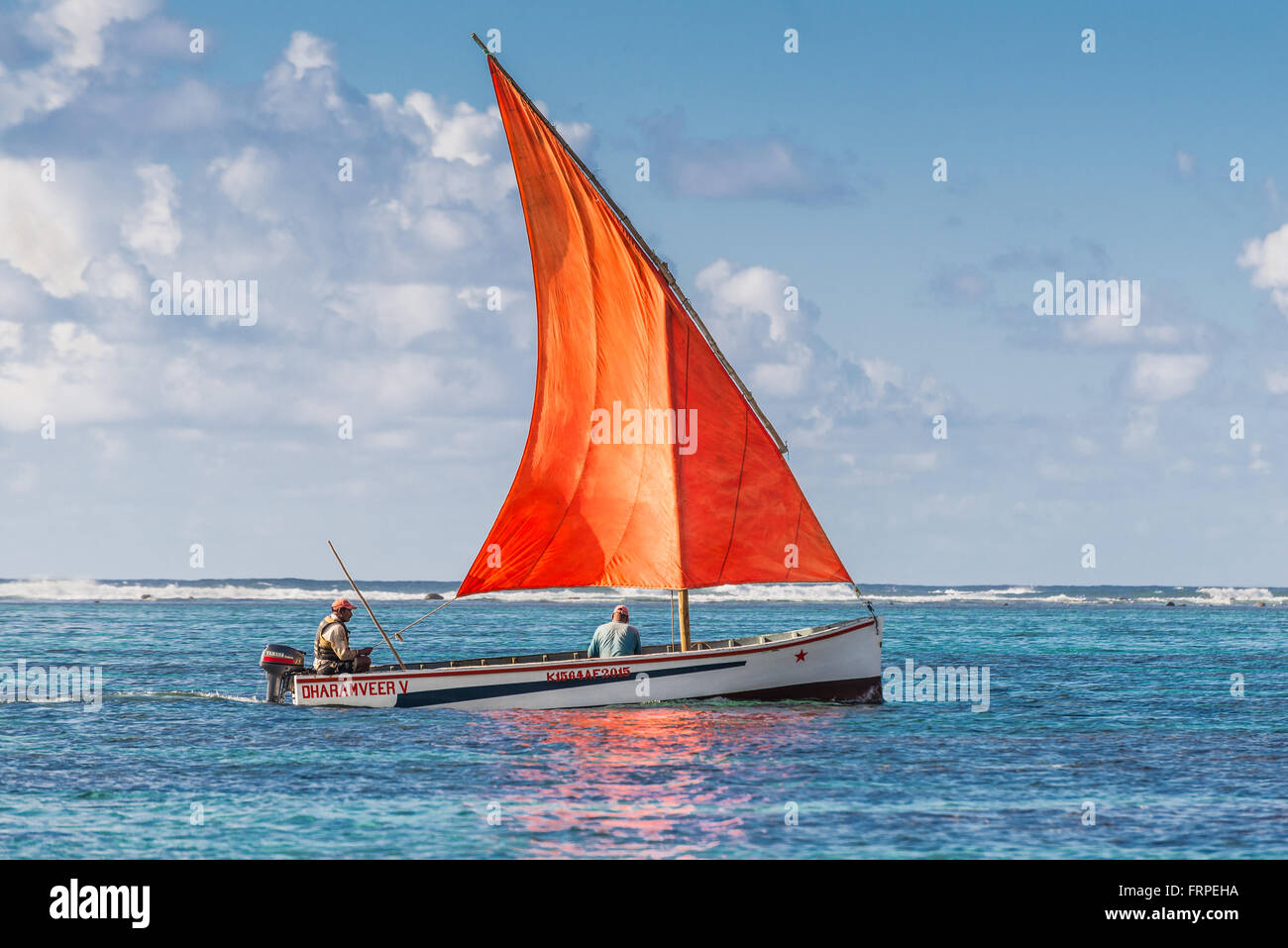 El bote con una vela roja en el Océano Indico - mar bella escena en la Bahía Azul, Mauricio. Foto de stock