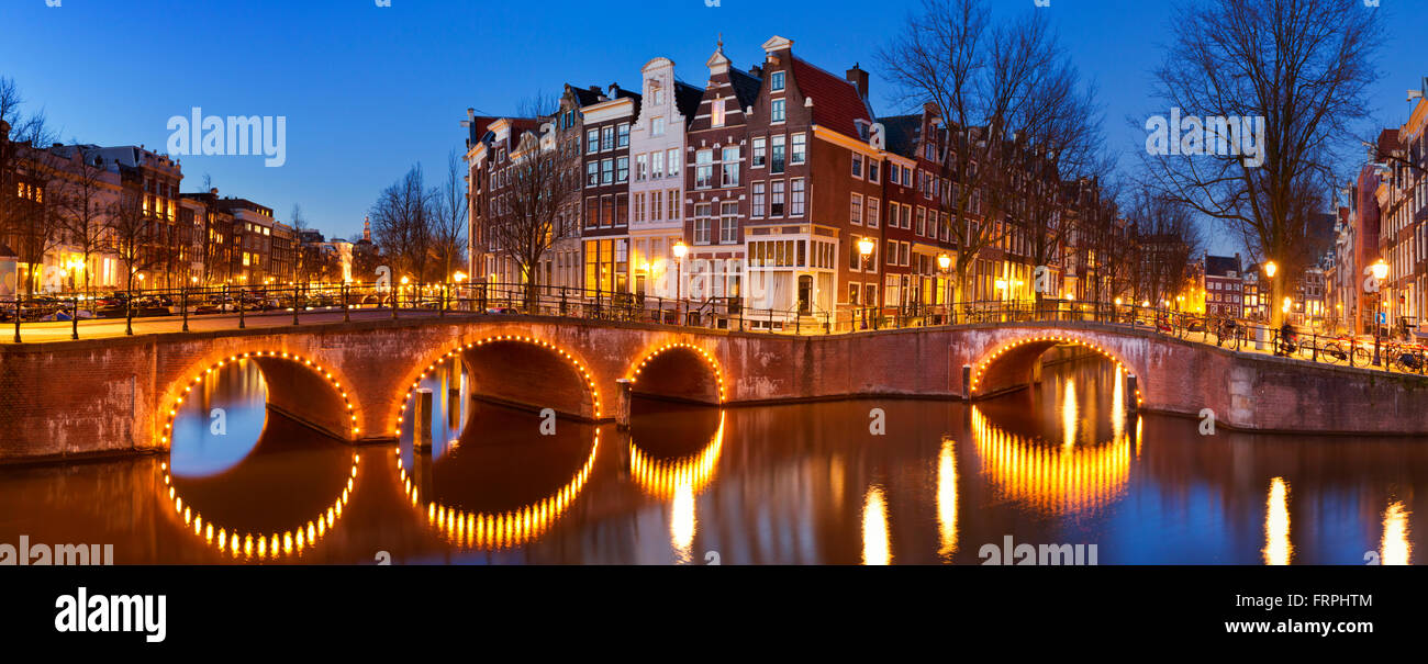 Puentes sobre el cruce de canales en la ciudad de Amsterdam, en los Países Bajos durante la noche. Foto de stock