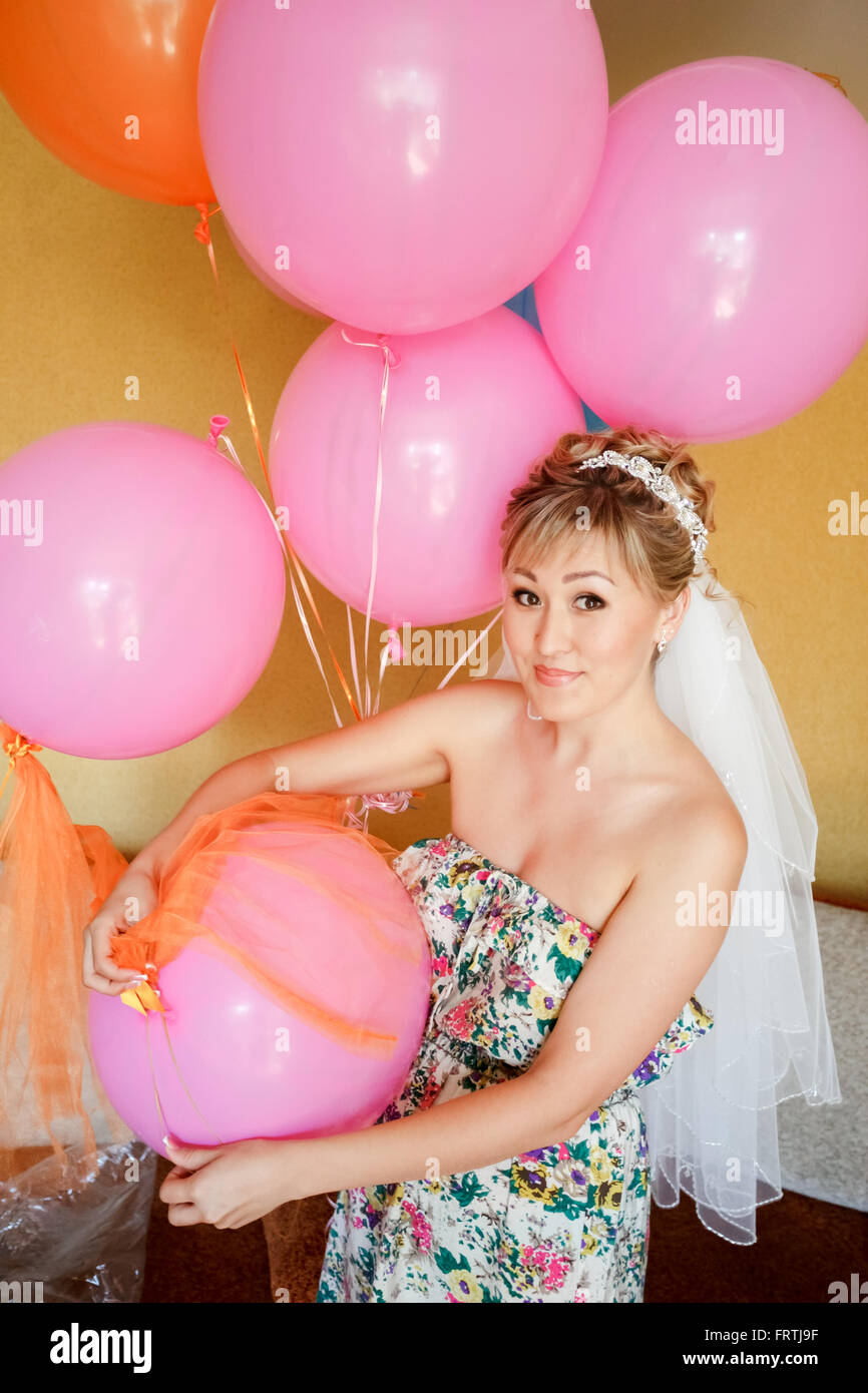 Novia ropa casual con velo entre globos rosa, preparándose para la boda. Foto de stock