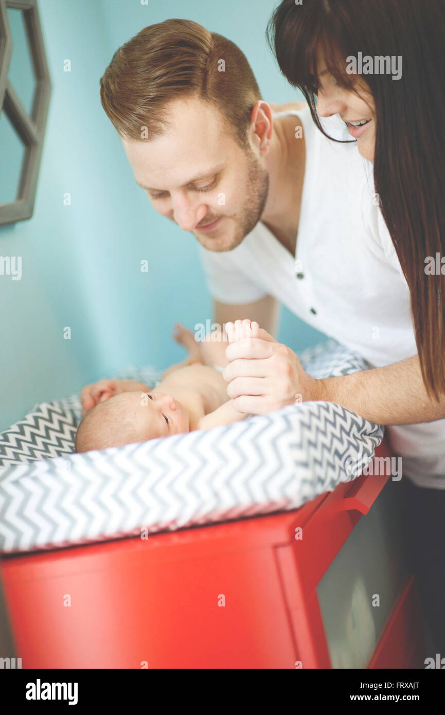 El padre y la madre mira nueva Baby Boy después de un cambio de pañal Foto de stock