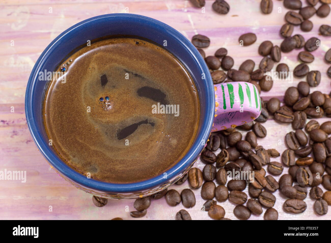 Taza de café y granos de café en una mesa de madera Foto de stock