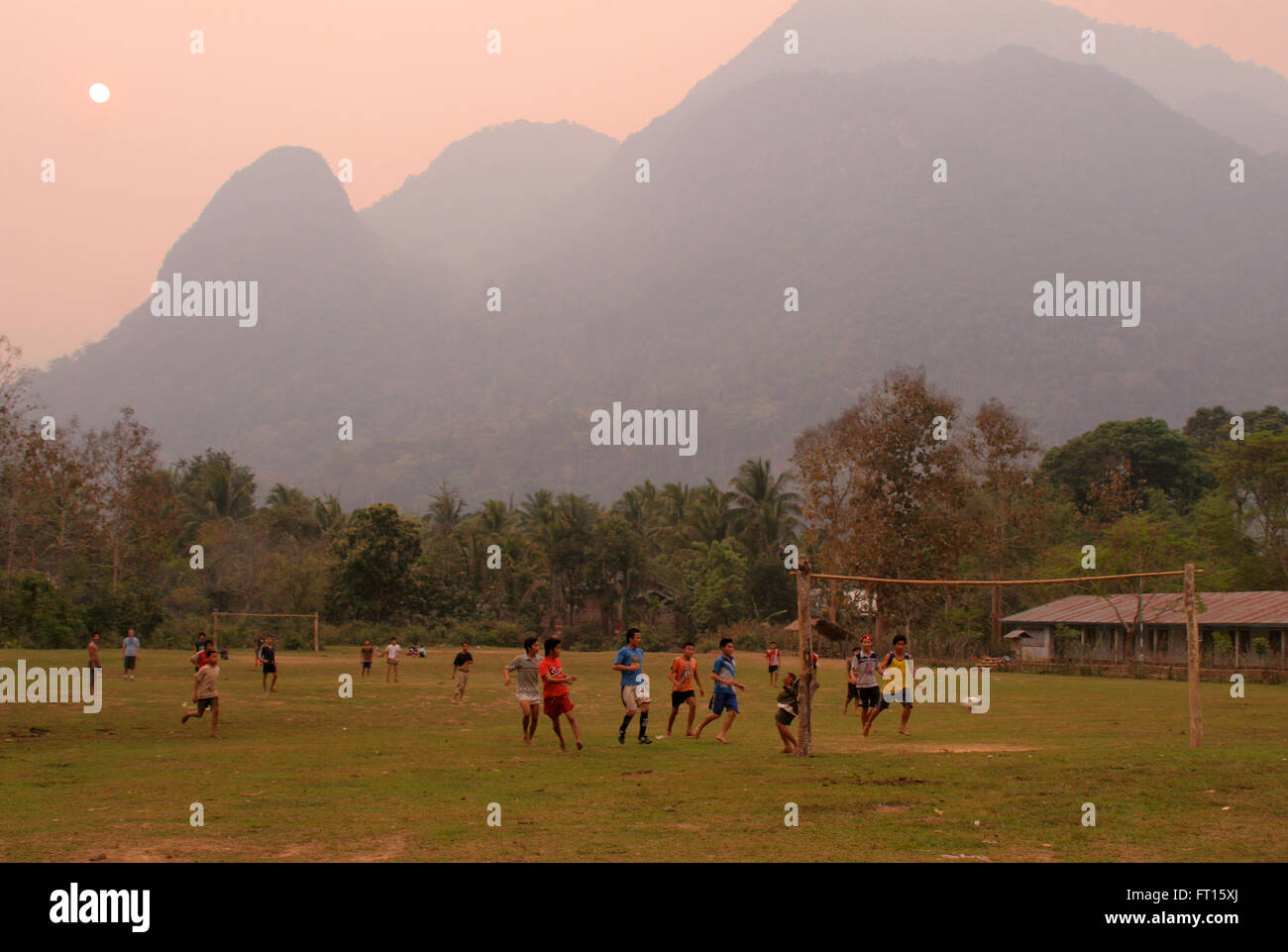 Muchachos jugando al fútbol, con montañas al fondo Foto de stock