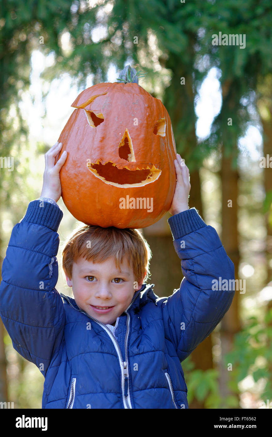 Boy a balancear una calabaza de Halloween en la cabeza en el otoño, Baviera, Alemania Foto de stock