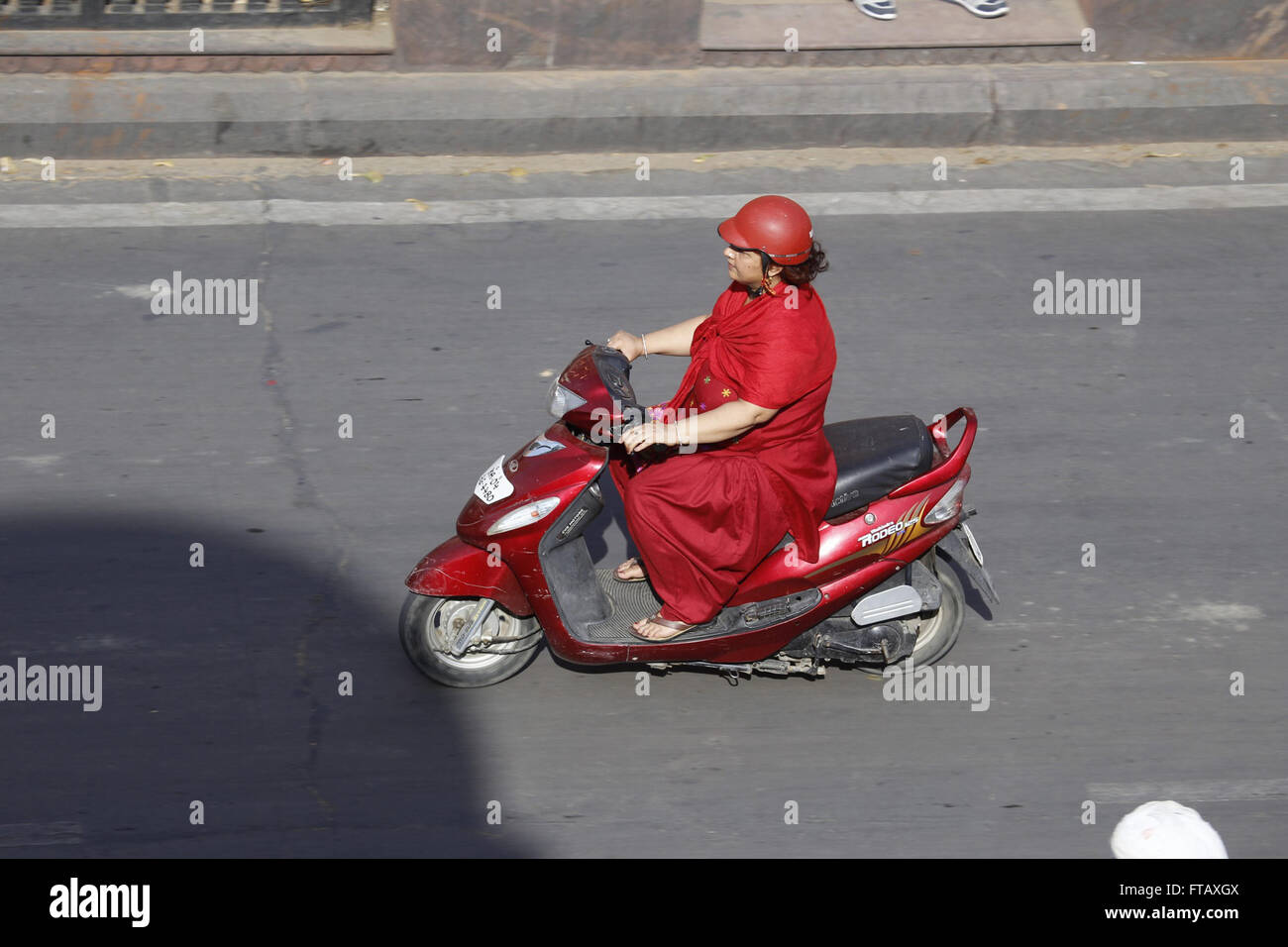 Jaipur, Rajasthan, India. Mujer en Rojo Sari en un escúter Foto de stock