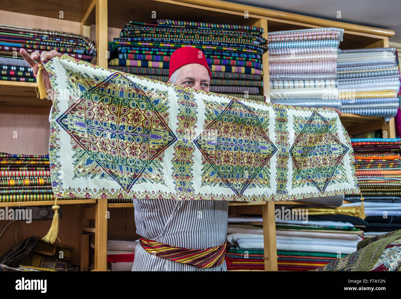Abu Khalaf, comerciante de telas importadas de oriente, muestra de textiles en su tienda en un mercado de la Ciudad Vieja de Jerusalén, Israel Fotografía de stock - Alamy