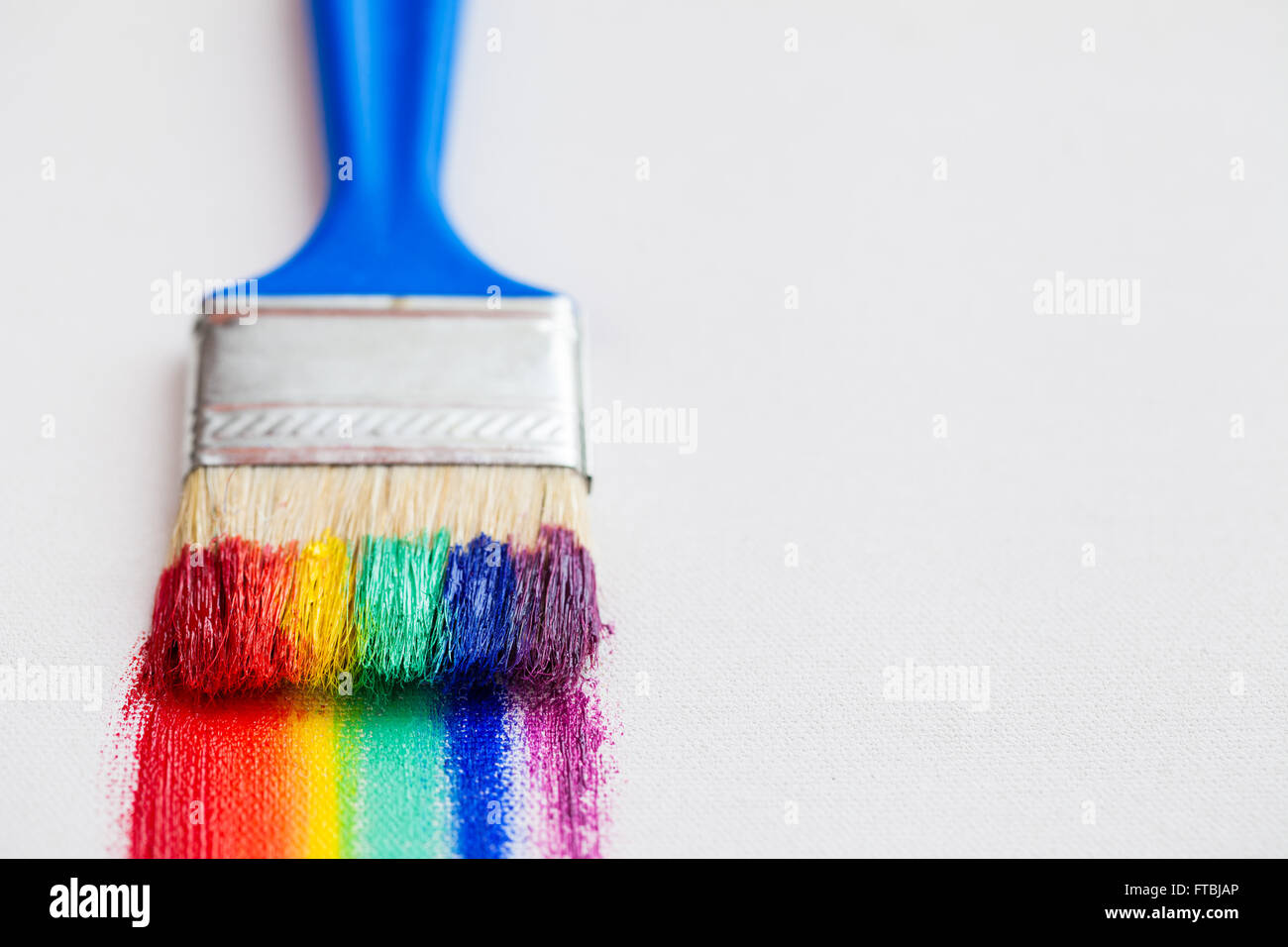 Pincel closeup y arco iris multicolor trazos de pincel sobre lienzo blanco Foto de stock