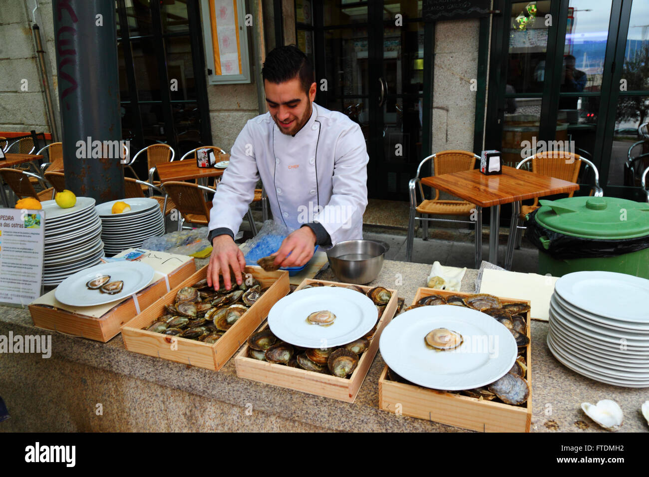 Hombre Ordenar por tamaño ostras fuera del restaurante de mariscos, Vigo, Galicia, España Foto de stock