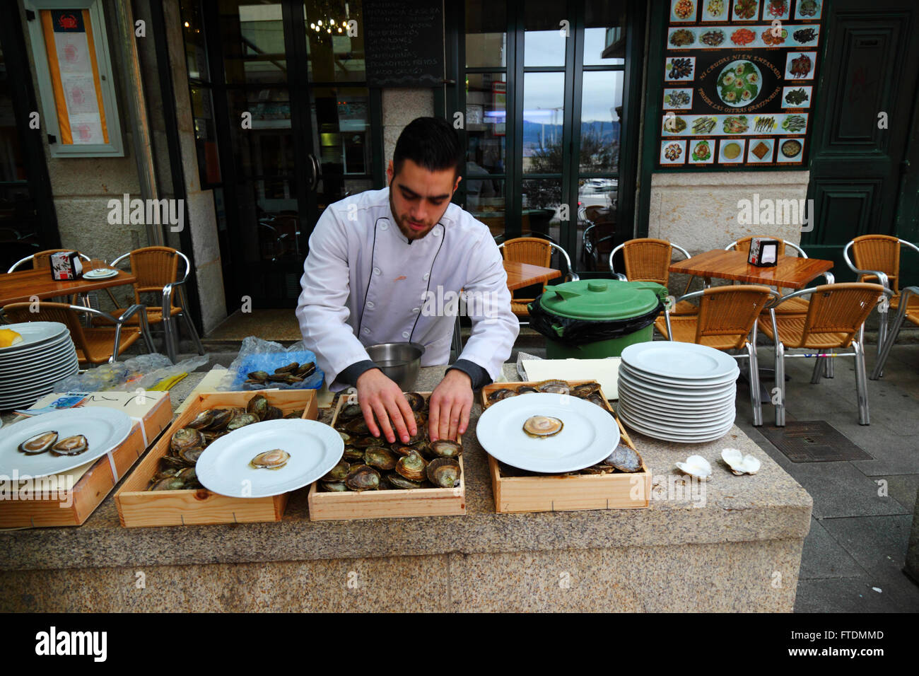 Hombre Ordenar por tamaño ostras fuera del restaurante de mariscos, Vigo, Galicia, España Foto de stock