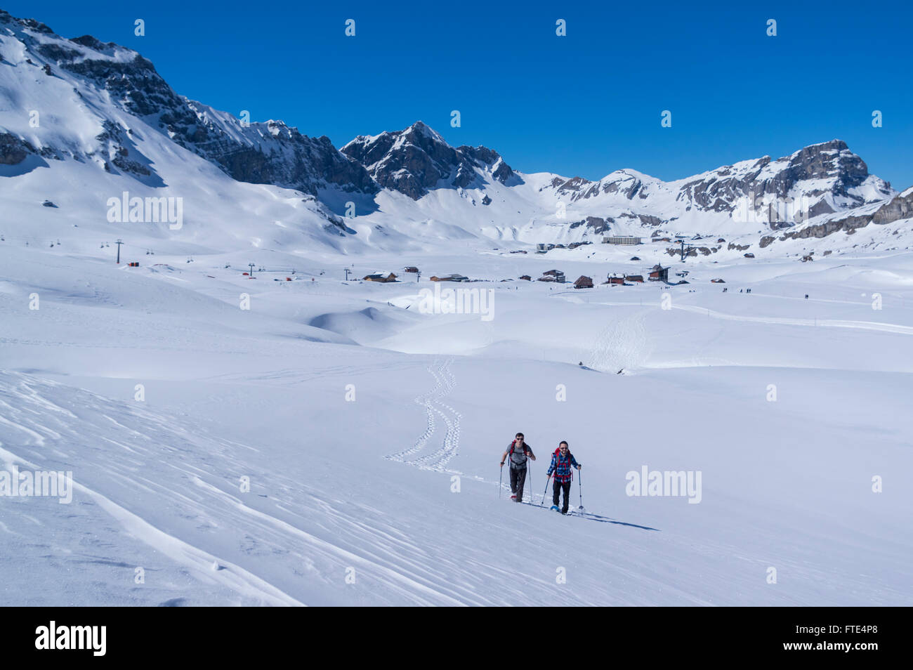 Dos hombres de senderismo con raquetas de nieve por los excursionistas en un soleado día de invierno en los Alpes Suizos. Melchsee-Frutt, Cantón de Unterwalden Alto, Suiza. Foto de stock