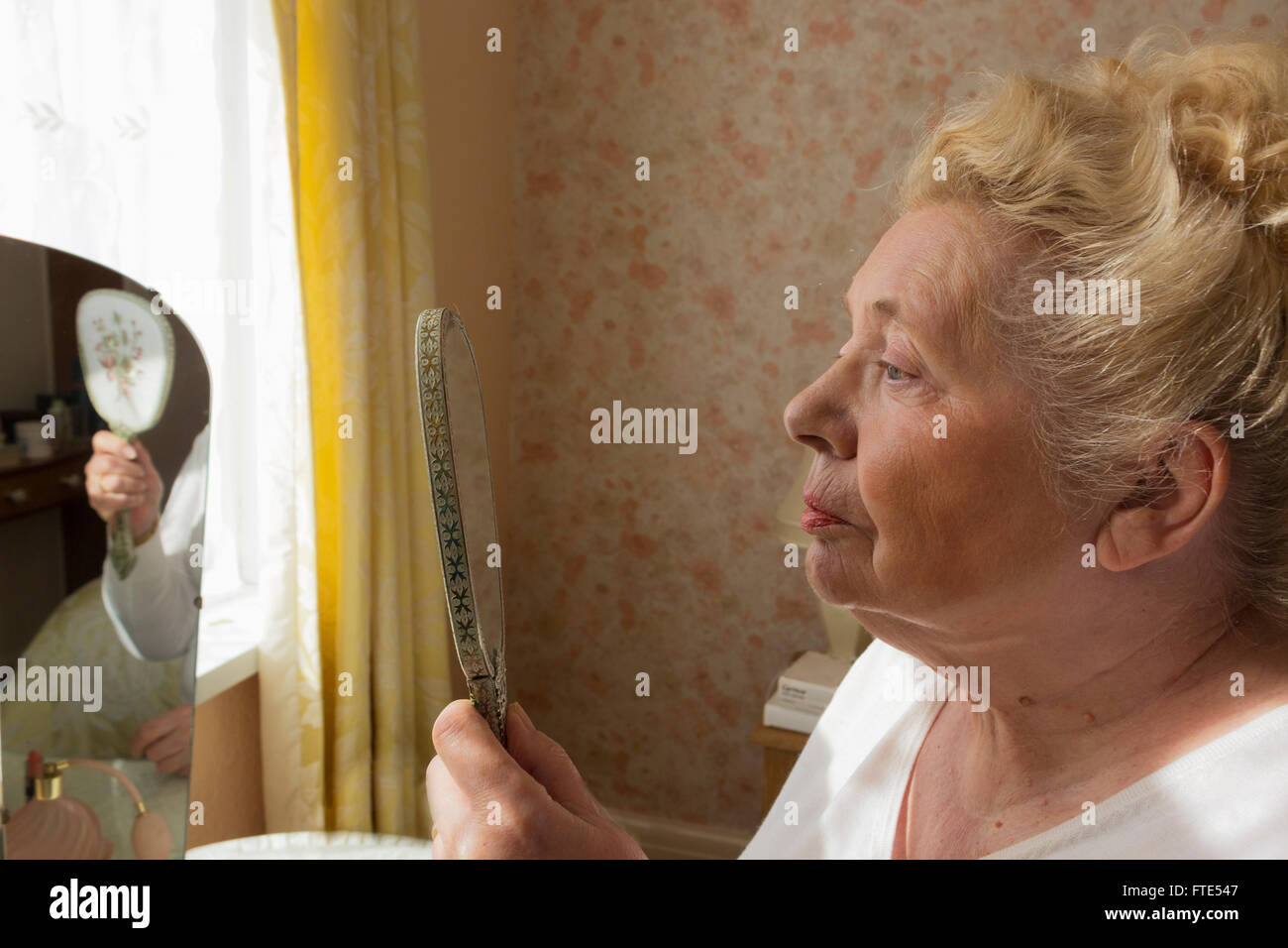 Anciana mirando su reflejo en un espejo de mano. Foto de stock