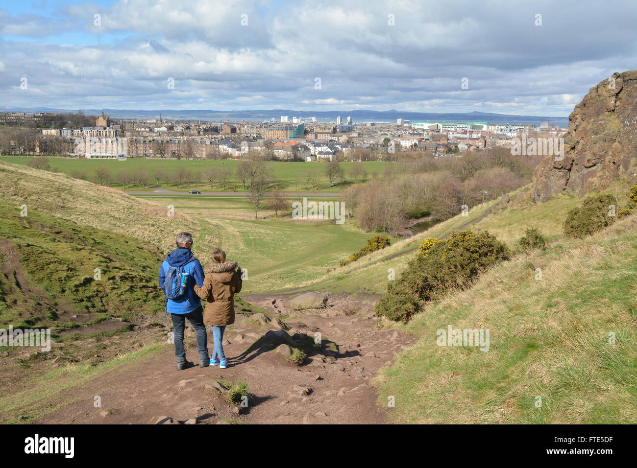 Dos personas disfrutando de una vista de Edimburgo en primavera mientras caminan hacia de Arthur's Seat en Holyrood Park Foto de stock