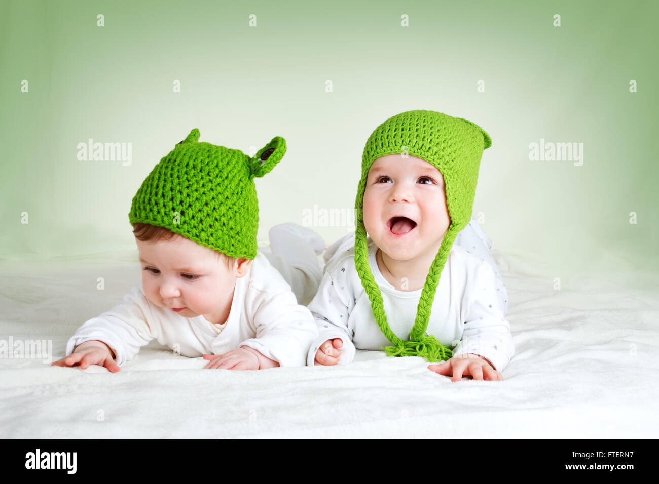Dos lindos bebés acostado en rana en Manta spft sombreros Foto de stock