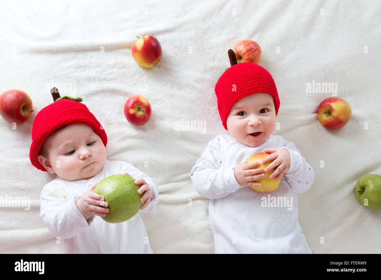Dos lindos bebés acostado en sombreros en Manta suave con manzanas Foto de stock