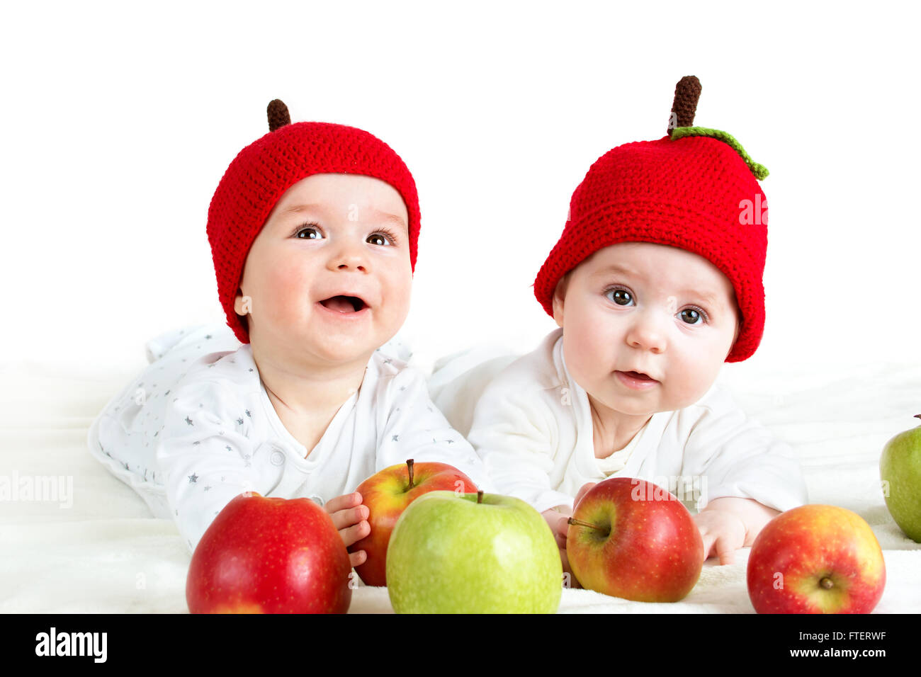 Dos lindos bebés acostado en sombreros en Manta suave con manzanas Foto de stock