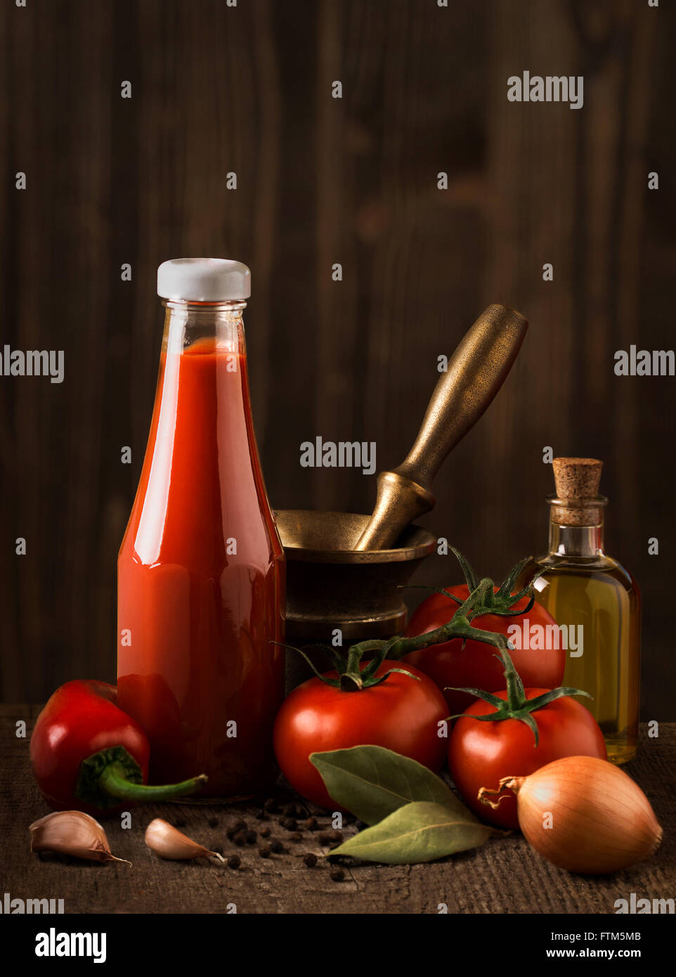 Still life oscuro con salsa de tomate y los ingredientes sobre la madera en bruto Foto de stock
