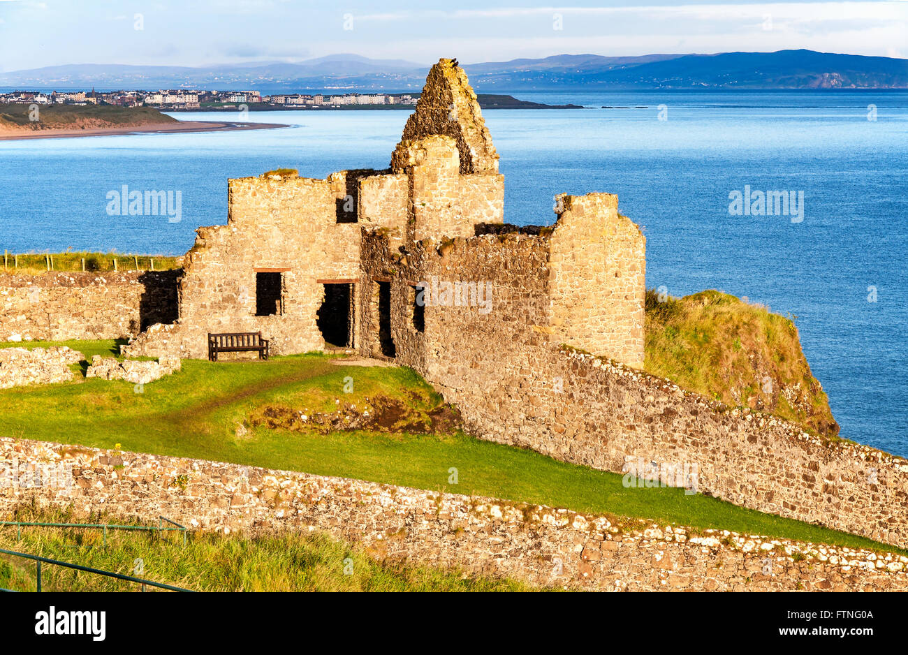 Fragmento de las ruinas del Castillo de Dunluce en el Condado de Antrim, Irlanda del Norte, Reino Unido, con la vista lejana de Portrush resort Foto de stock