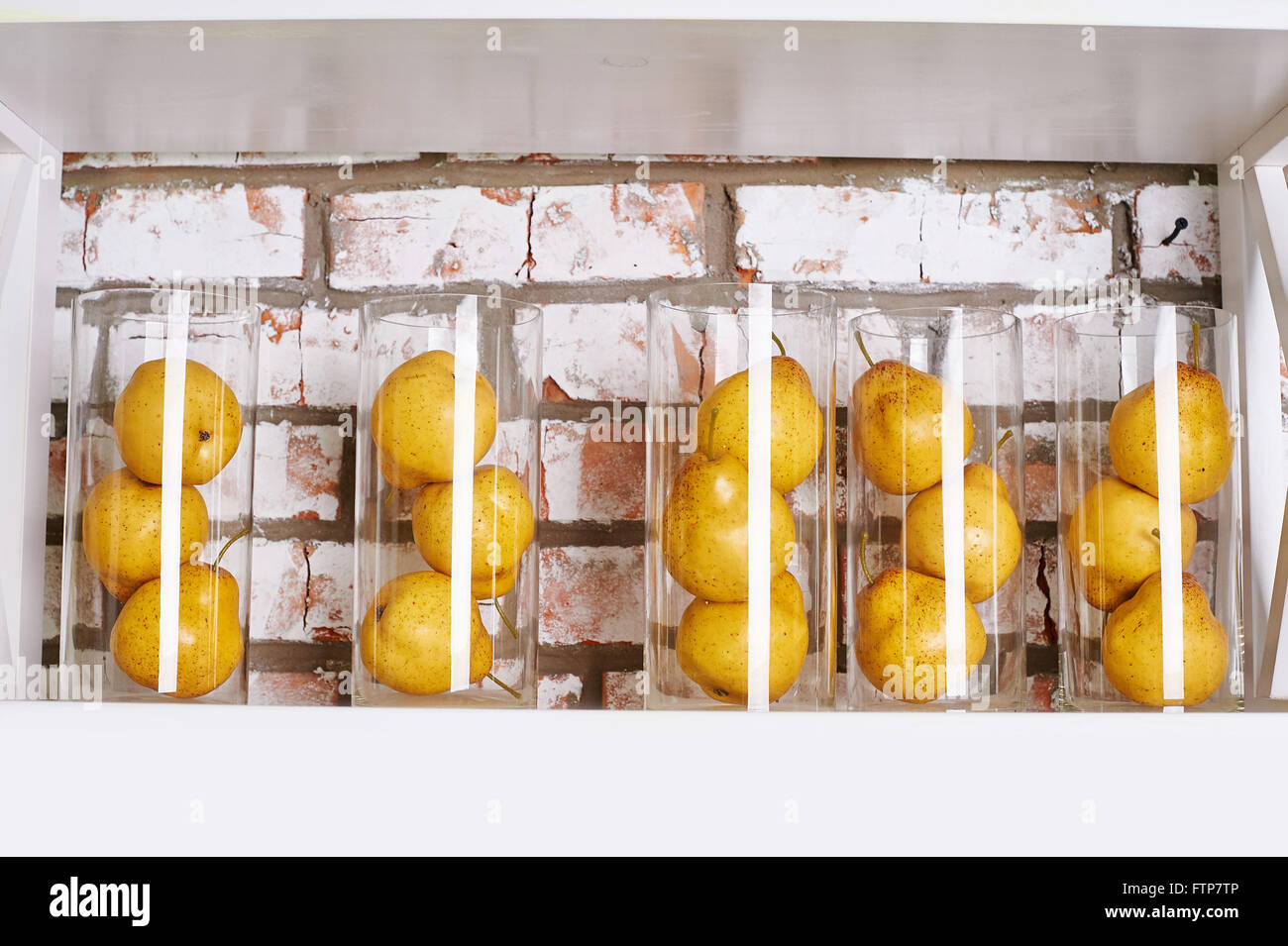 Las peras en amarillo pequeño de vidrio en la estantería del concepto de la vida todavía Foto de stock