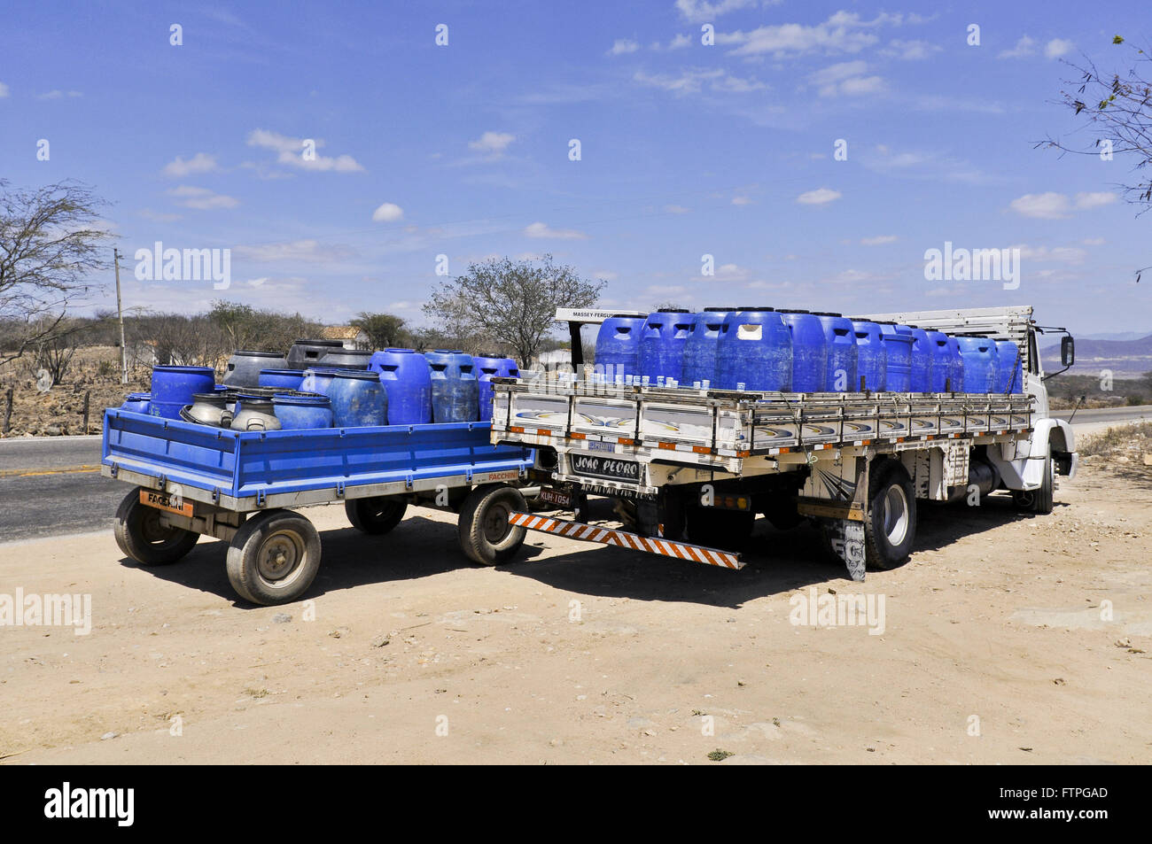 Camión tractor y transportar agua potable en galones durante la sequía Foto de stock