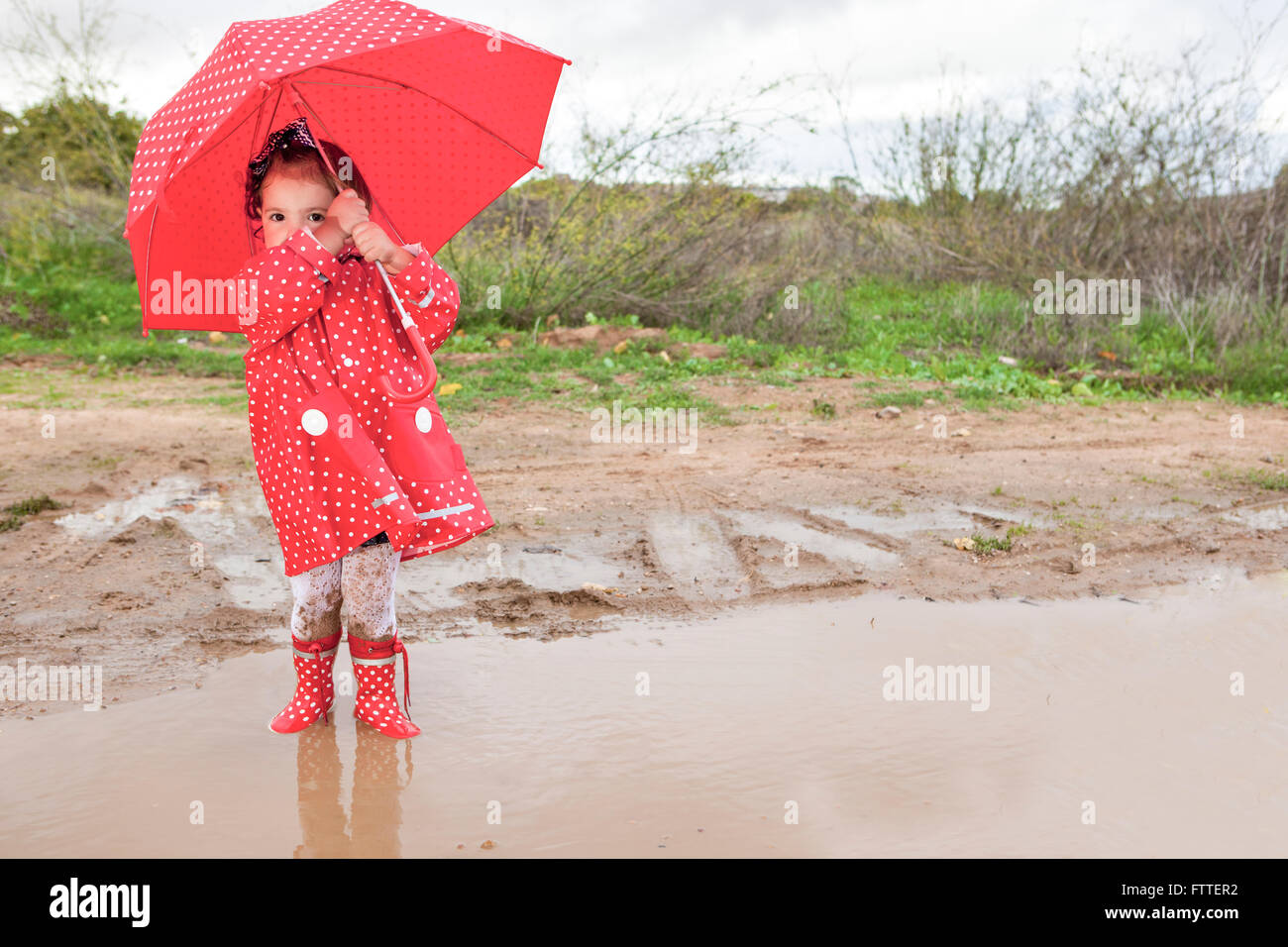 Bebé niña vestido con impermeable y paraguas punteado un típico día ventoso  y lluvioso de otoño Fotografía de stock - Alamy