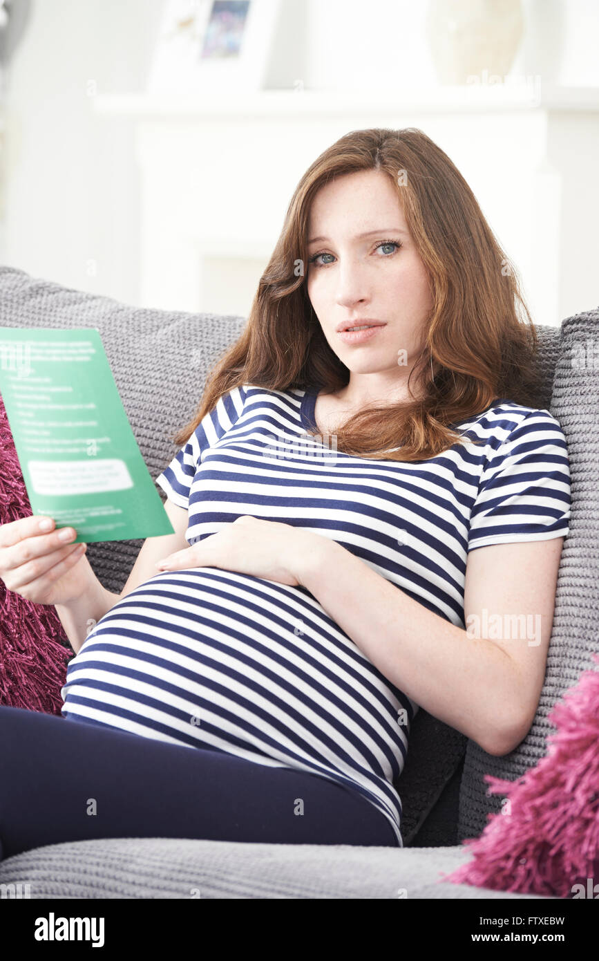 Embarazada interesada leyendo folleto con consejos médicos Foto de stock