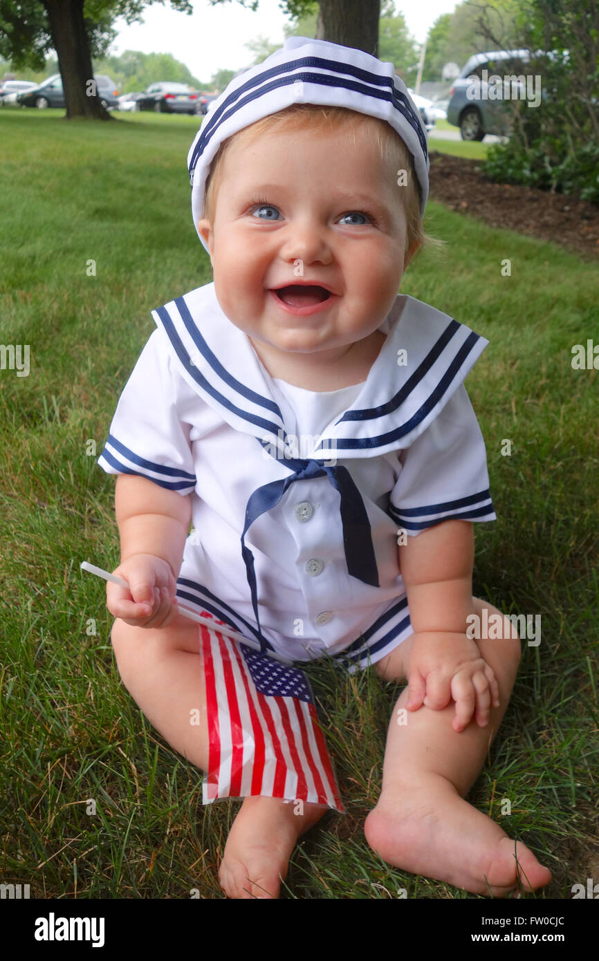 Bebé vestido como marinero, con bandera americana julio de Fotografía de stock