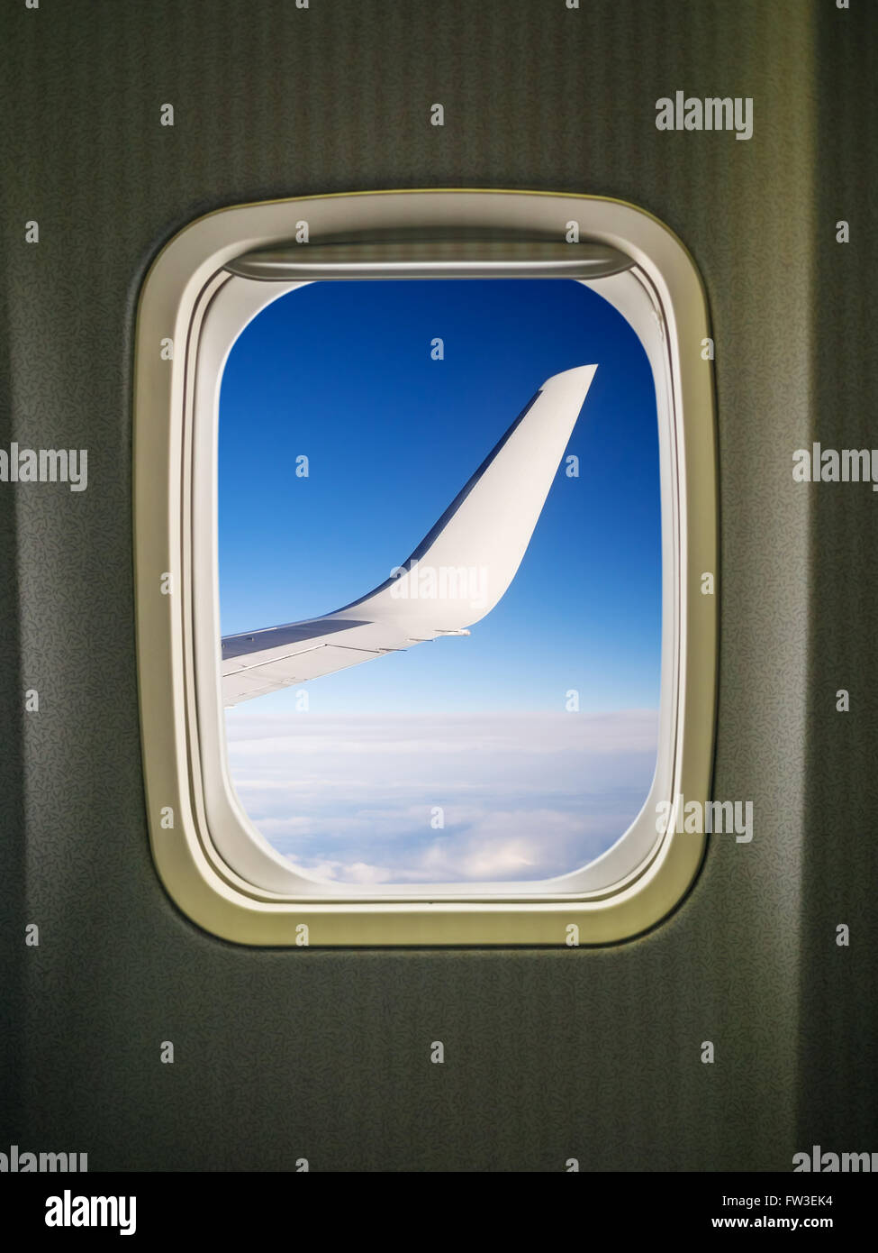 Vista de ala y cielo azul a través de la ventana de avión Foto de stock