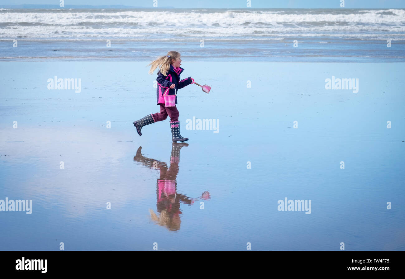 Una niña jugando en una playa vacía en Westward Ho!, Devon en el REINO UNIDO Foto de stock