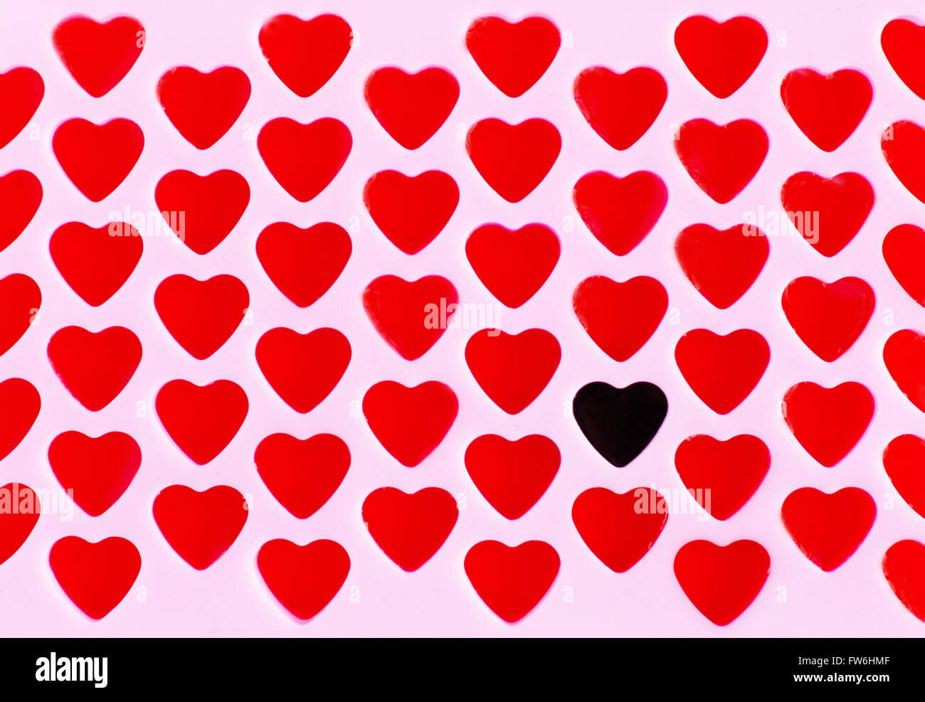 Un corazón negro en un patrón de Corazones rojos. Foto de stock