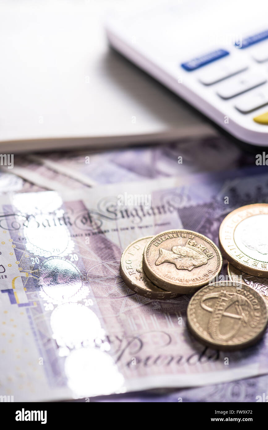 Libras esterlinas monedas y billetes en la mesa con la calculadora  Fotografía de stock - Alamy