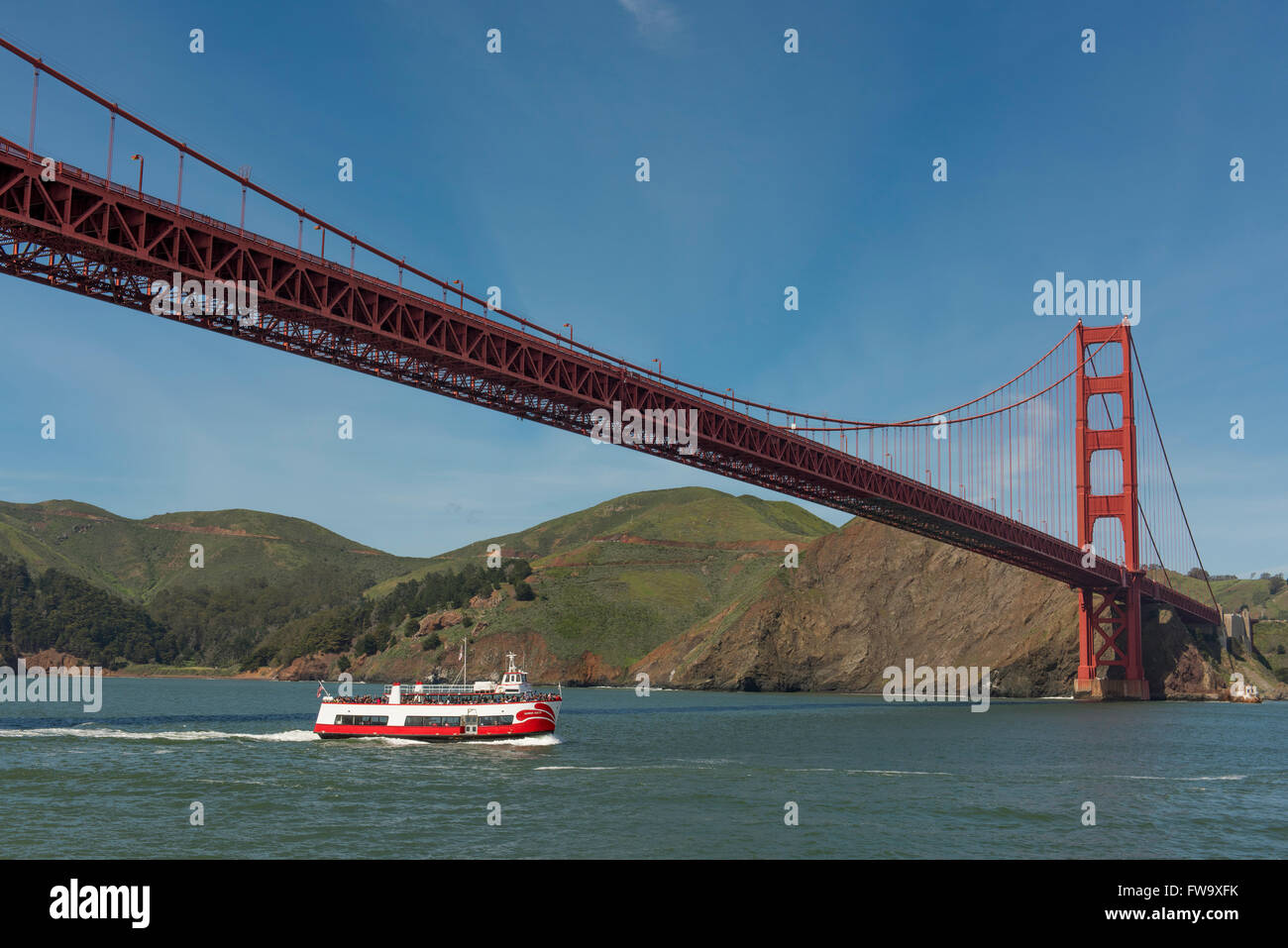 El Puente Golden Gate con paseos en barco pasando por debajo, cerca de San Francisco, California, EE.UU. Foto de stock