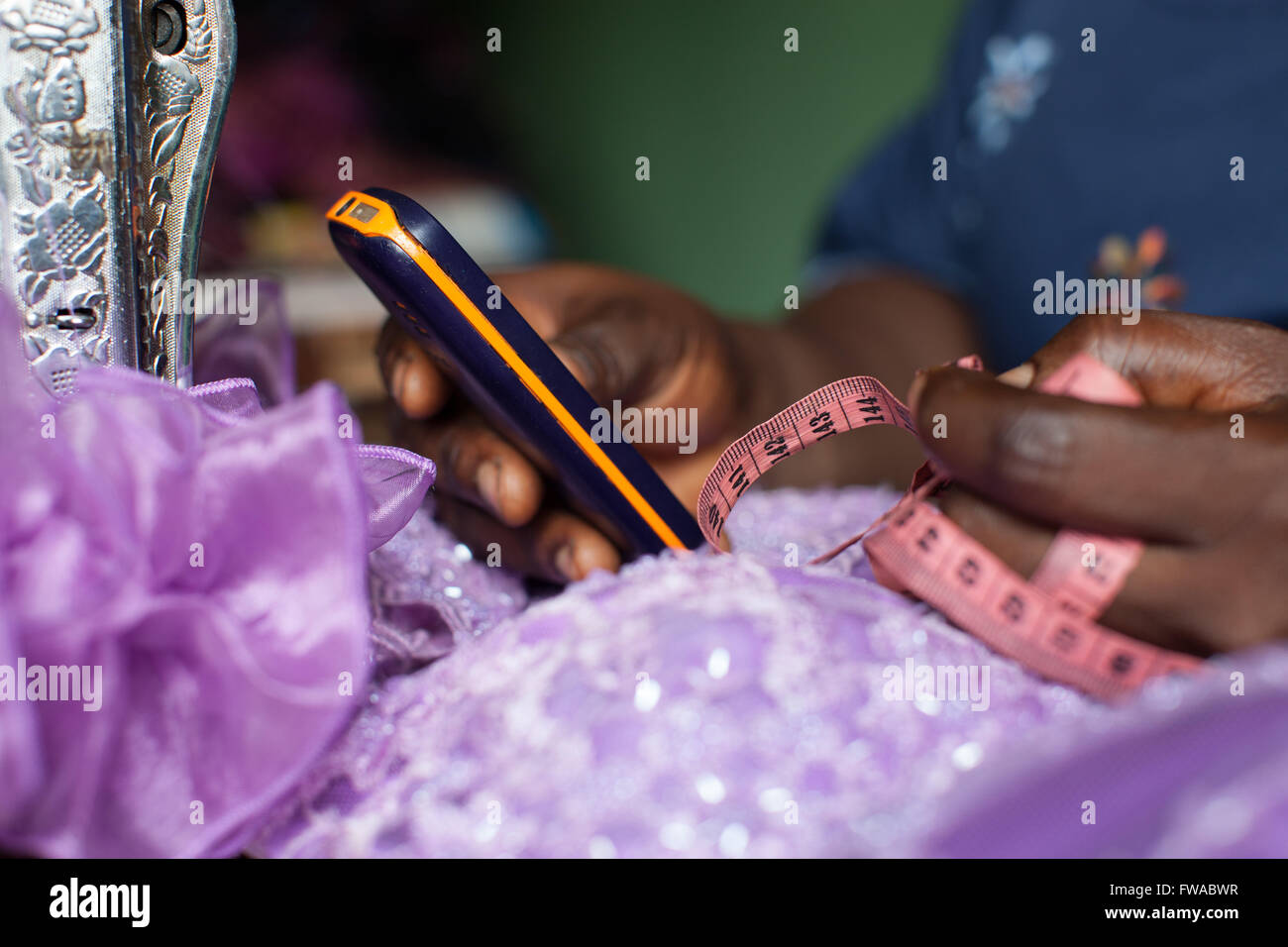 Una vestimenta femenina maker usando su móvil para negocios, Nigeria, África Foto de stock