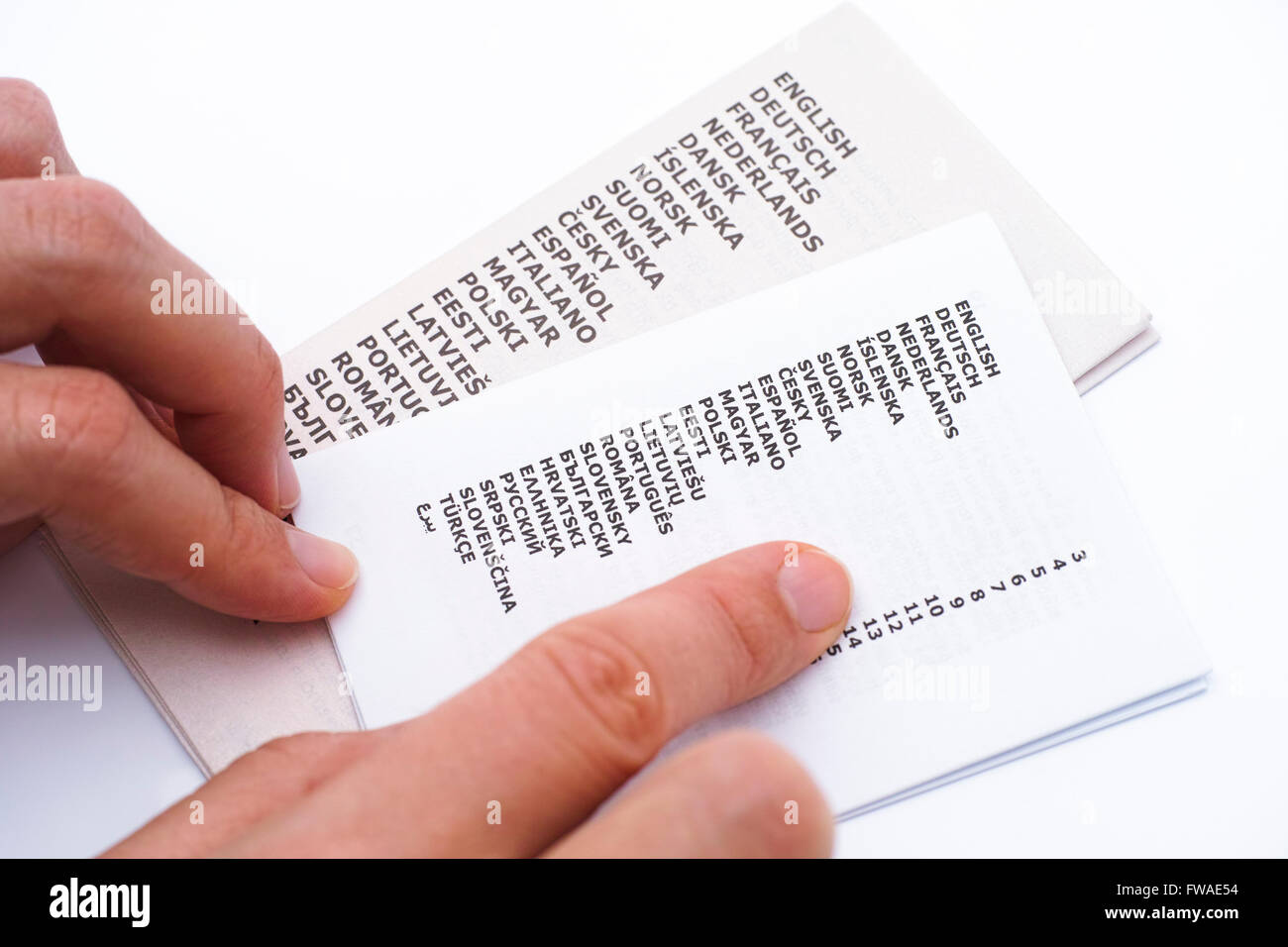 Folleto con la lista de idiomas y mujer manos. Fondo blanco. Foto de stock