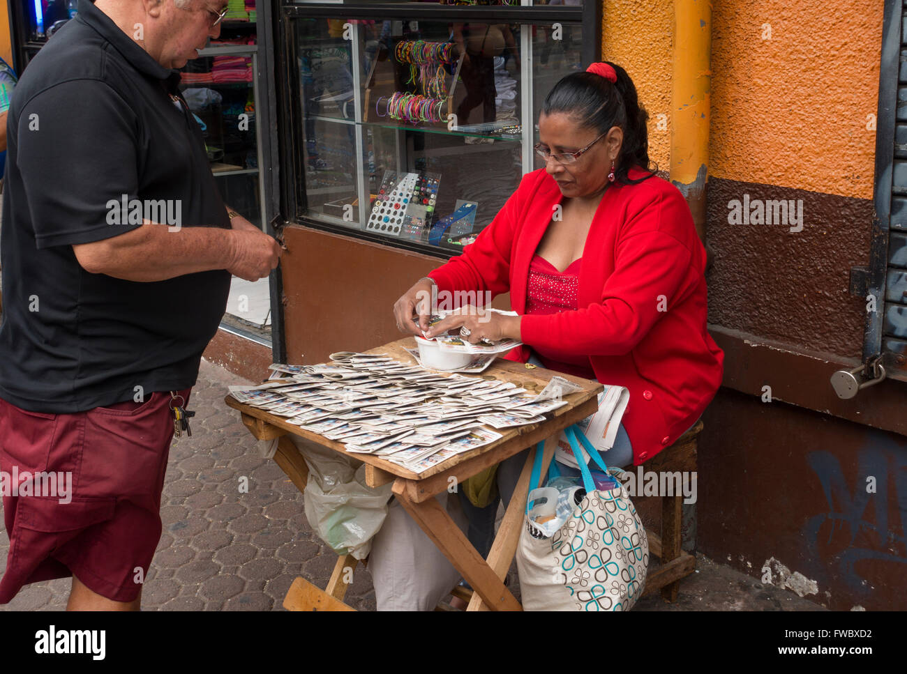 Una mujer que vende billetes de lotería a lo largo de la Avenida Central en San José, Provincia de San José, Costa Rica. Foto de stock