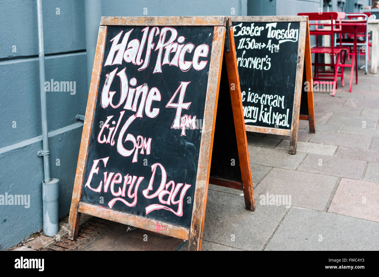Un pizarrón-boards fuera un pub cafe publicidad vino a mitad de precio entre las 4pm y las 6pm cada día. Foto de stock