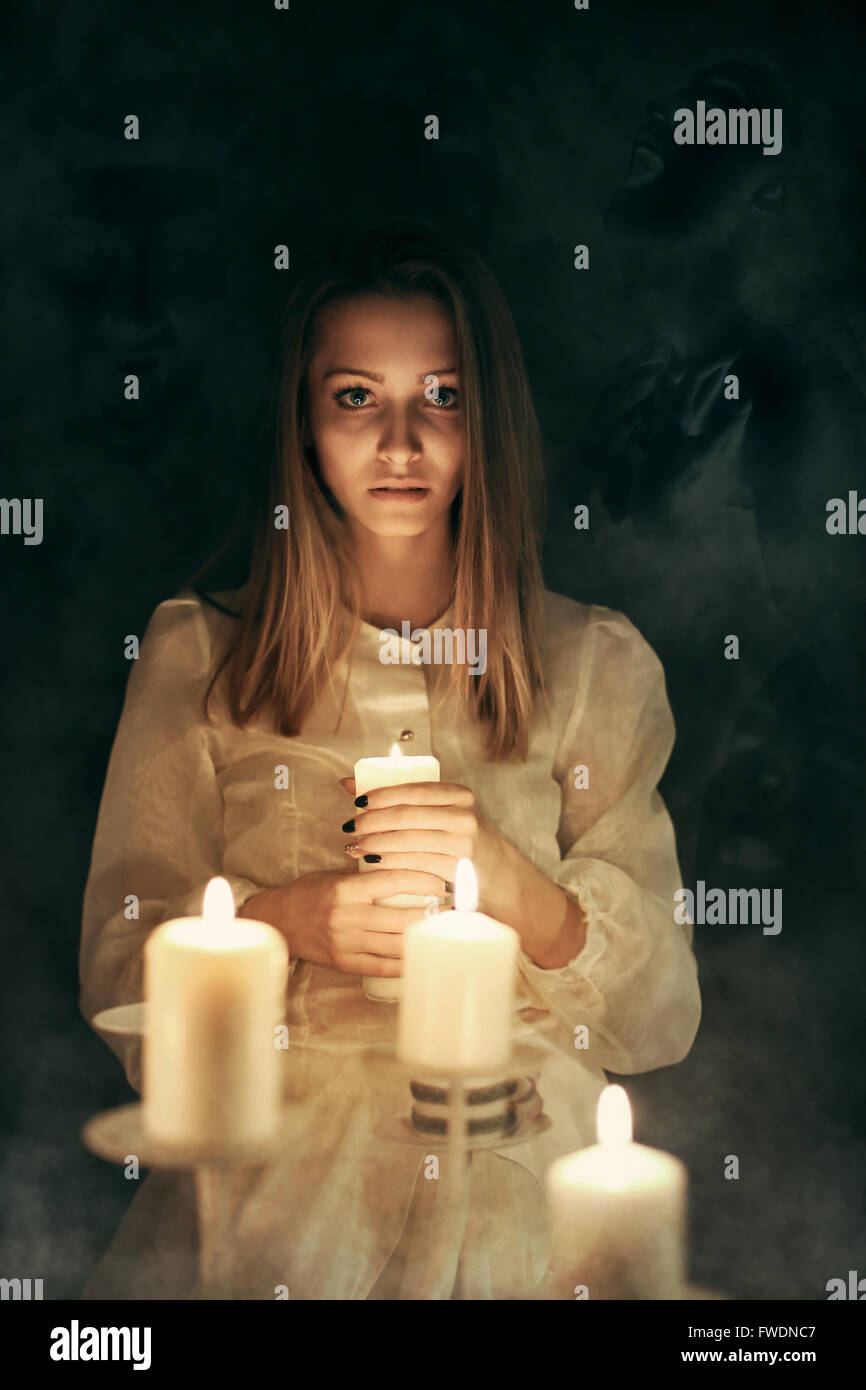 Mujer joven con la luz de las velas rodeado de fantasmas . Halloween y aterrador Foto de stock