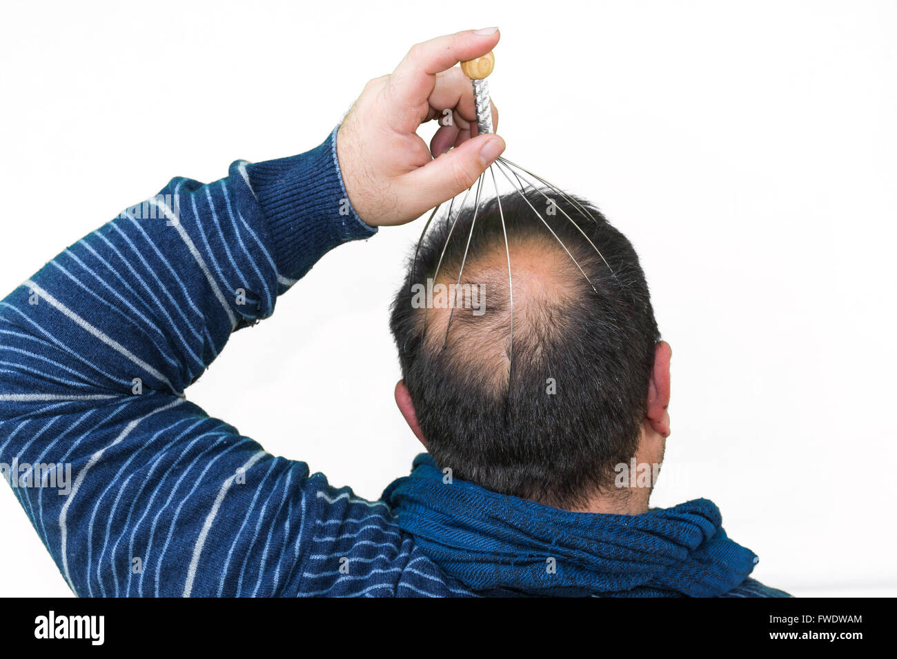 El hombre se relaja con el genio cabeza masajeador. Terapia alternativa. Masaje indio de cabeza herramienta, auto cabeza masajeador. Foto de stock