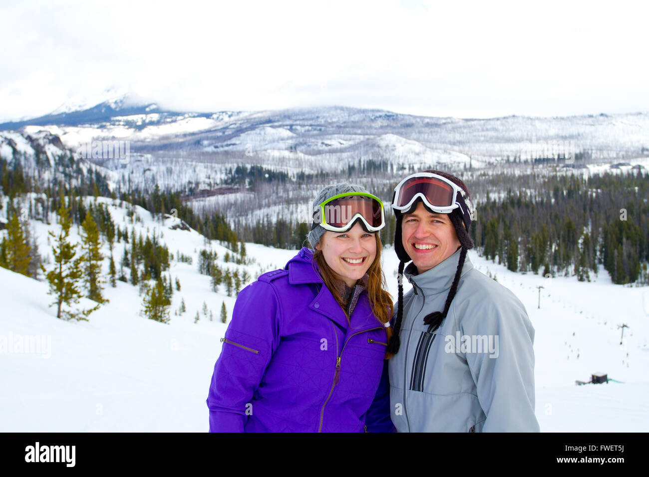 Una pareja feliz juntos en el resort de montaña en la nieve de un día de esquí y snowboard. Foto de stock