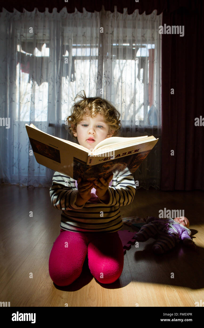 Retrato de niño con la lectura de un libro y la muñeca Foto de stock