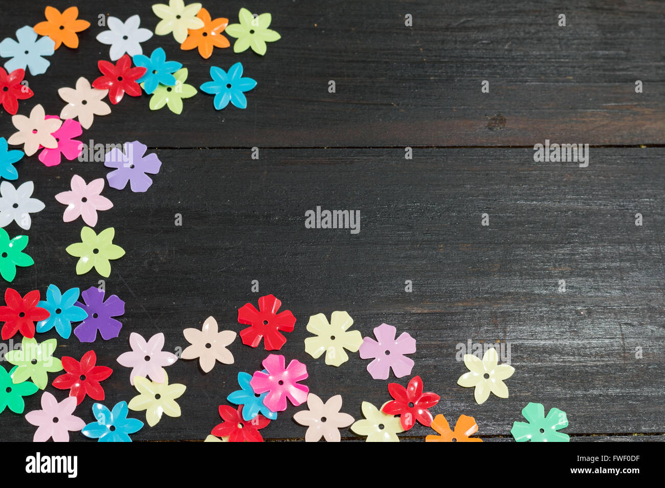 Mesa de madera negra con coloridas flores artificiales Foto de stock
