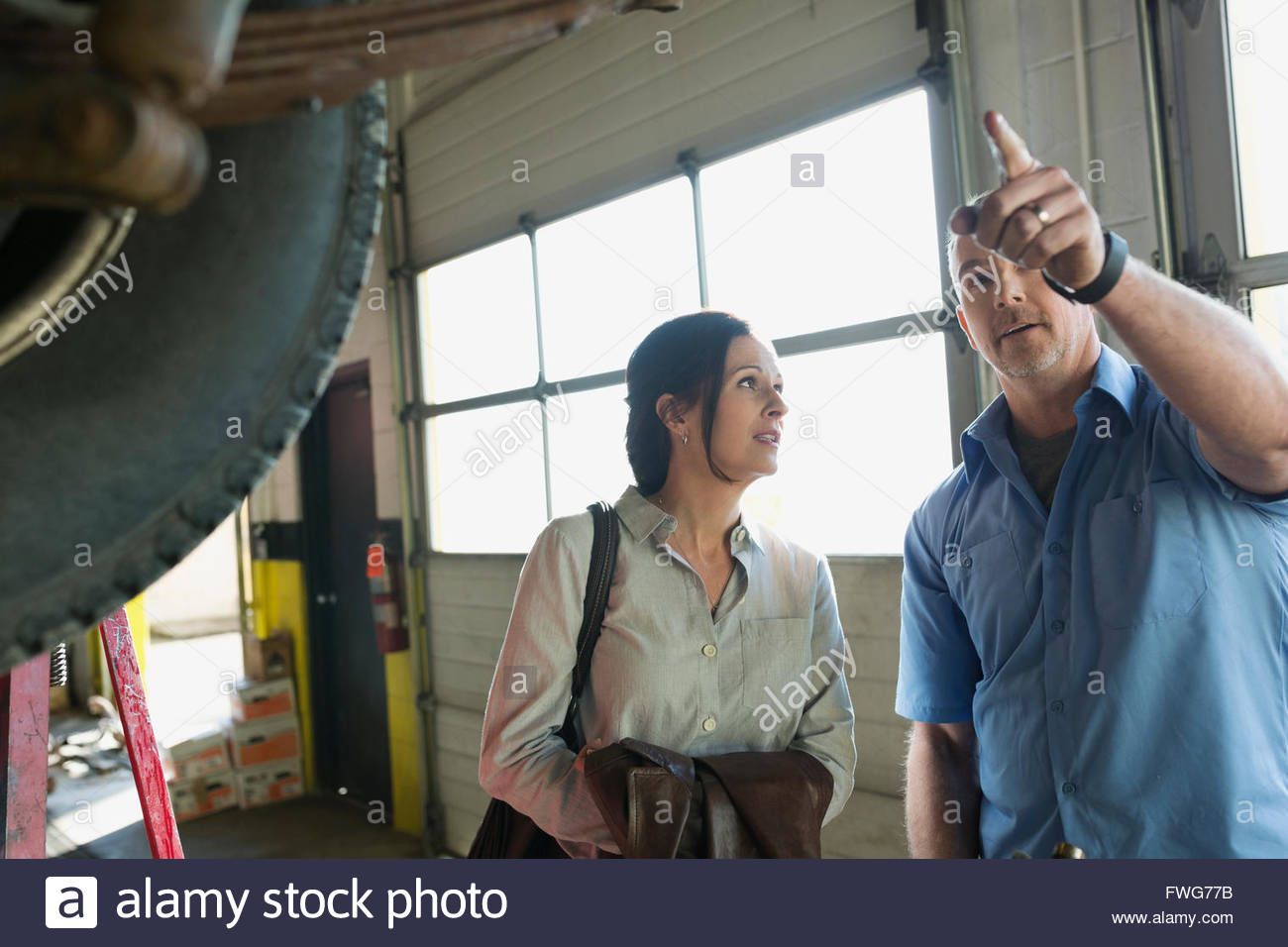 Mechanic explicando al cliente en taller de reparación de automóviles Foto de stock